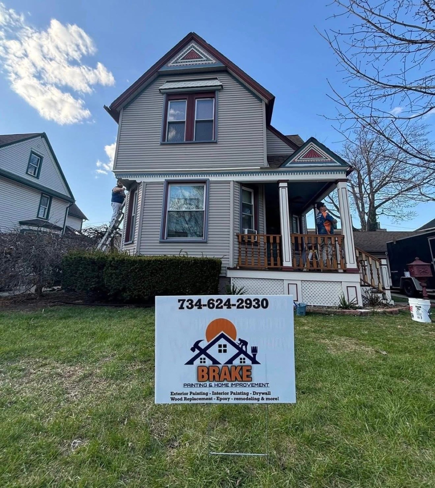 Two-and-a-half-story Victorian home being repainted gray with deep maroon trim, with a Brake Painting yard sign in the front lawn